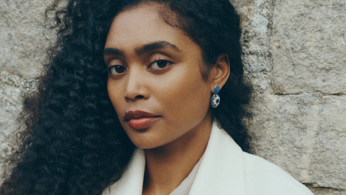 Woman wearing white blazer and blue gemstone earrings by Raphaëlle Coqblin fine jewelry